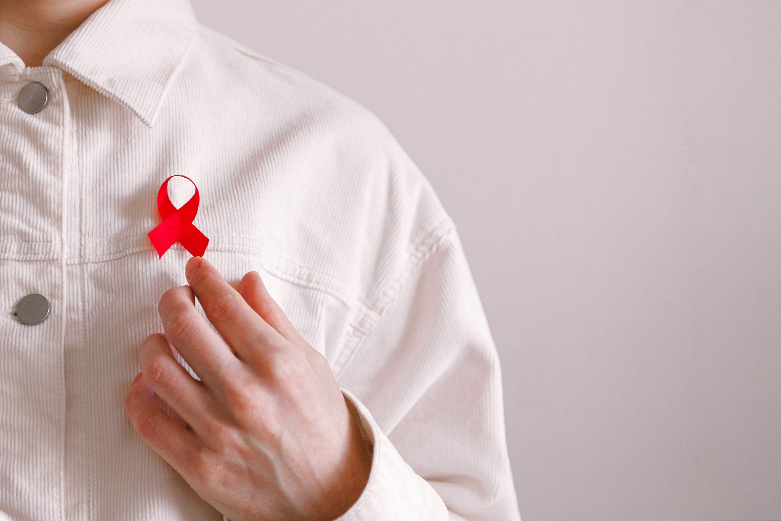 Muž s červenou stužkou na košili při příležitosti Světového dne boje proti AIDS